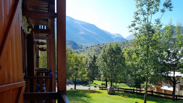 A wooden balcony with a view of a green lawn and distant mountains. - Mountain environment. Fireplace and garden - Isard 4 (Pla de l'Ermita)
