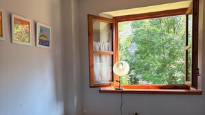 A room with two single beds, a window with a view of greenery, and a wall-mounted shelf with a lamp. - Mountain environment. Fireplace and garden - Isard 4 (Pla de l'Ermita)