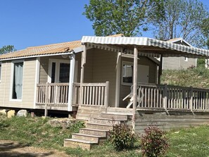 A mobile home with a porch, wooden steps, and a small garden area.