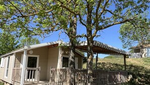 A single-story cabin with a porch, a covered area, and a fenced yard.