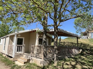 A single-story cabin with a porch, a covered area, and a fenced yard.