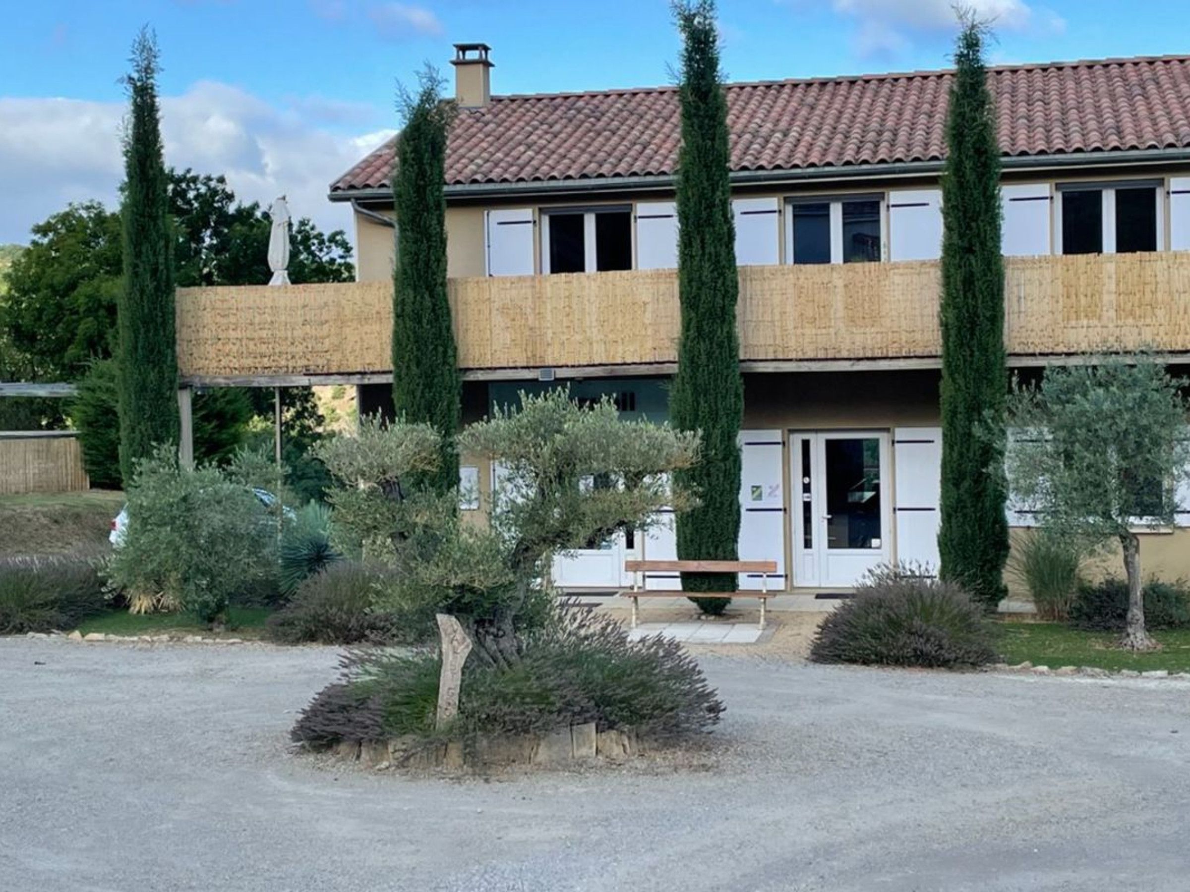 Un bâtiment à deux étages, doté d’un toit en tuiles, d’une entrée principale et d’une allée gravillonnée.