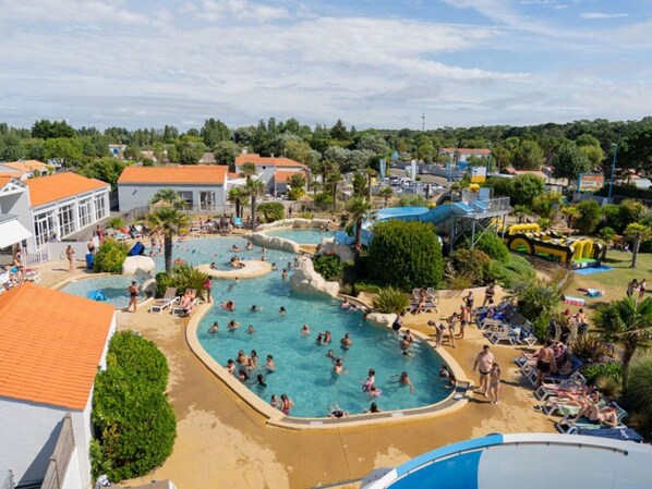 Una gran piscina al aire libre con múltiples fuentes y una zona de playa arenosa.