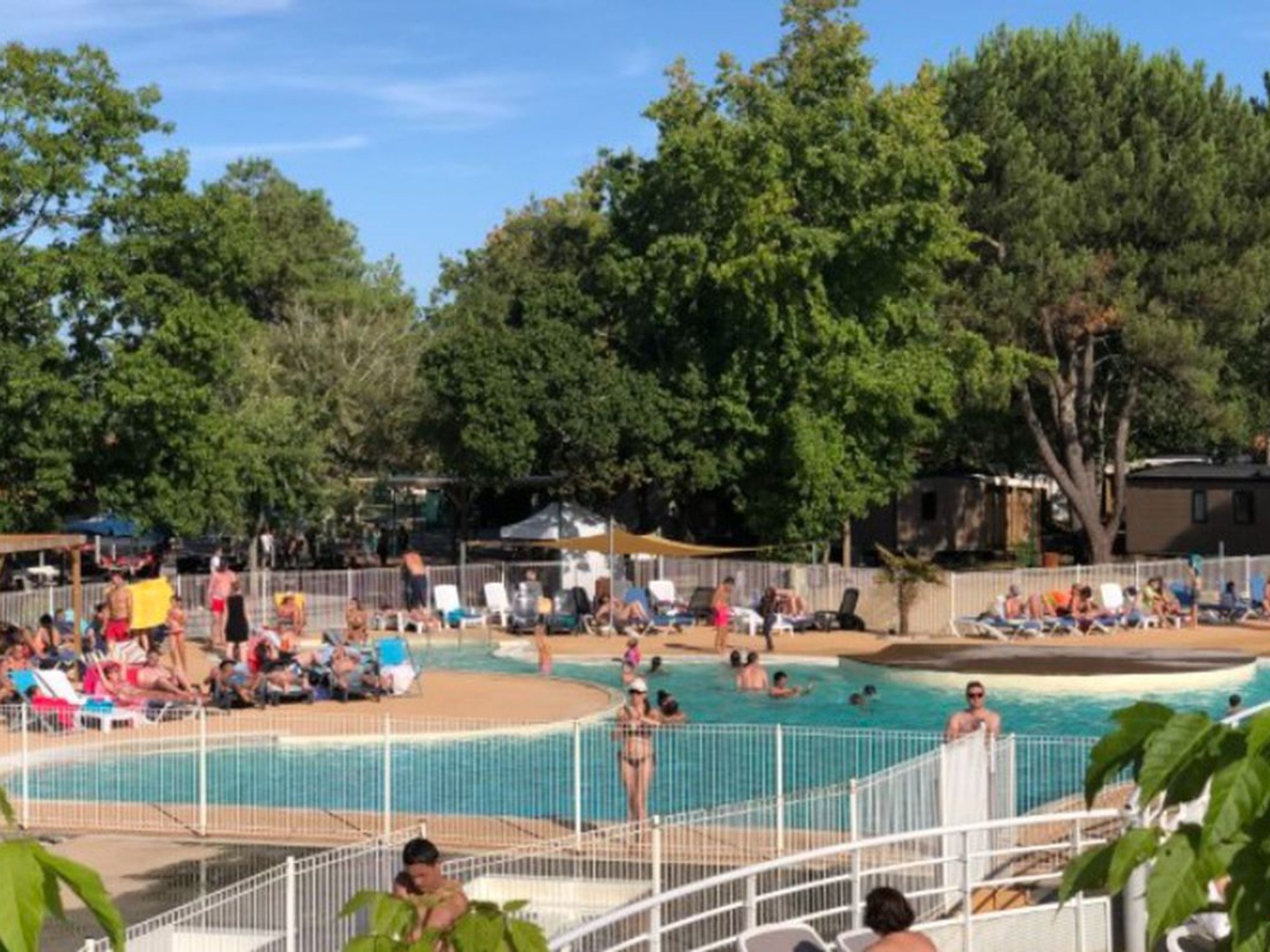 A pool area with multiple swimming pools, lounge chairs, and a fenced deck area.