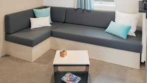Ein modernes Wohnzimmer mit einem grauen Ecksofa, einem weißen Couchtisch und einem Fenster mit Vorhängen.