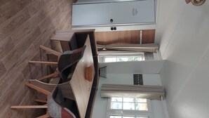 Een moderne keuken met een eethoek, houten vloeren en een raam dat voor natuurlijk licht zorgt.