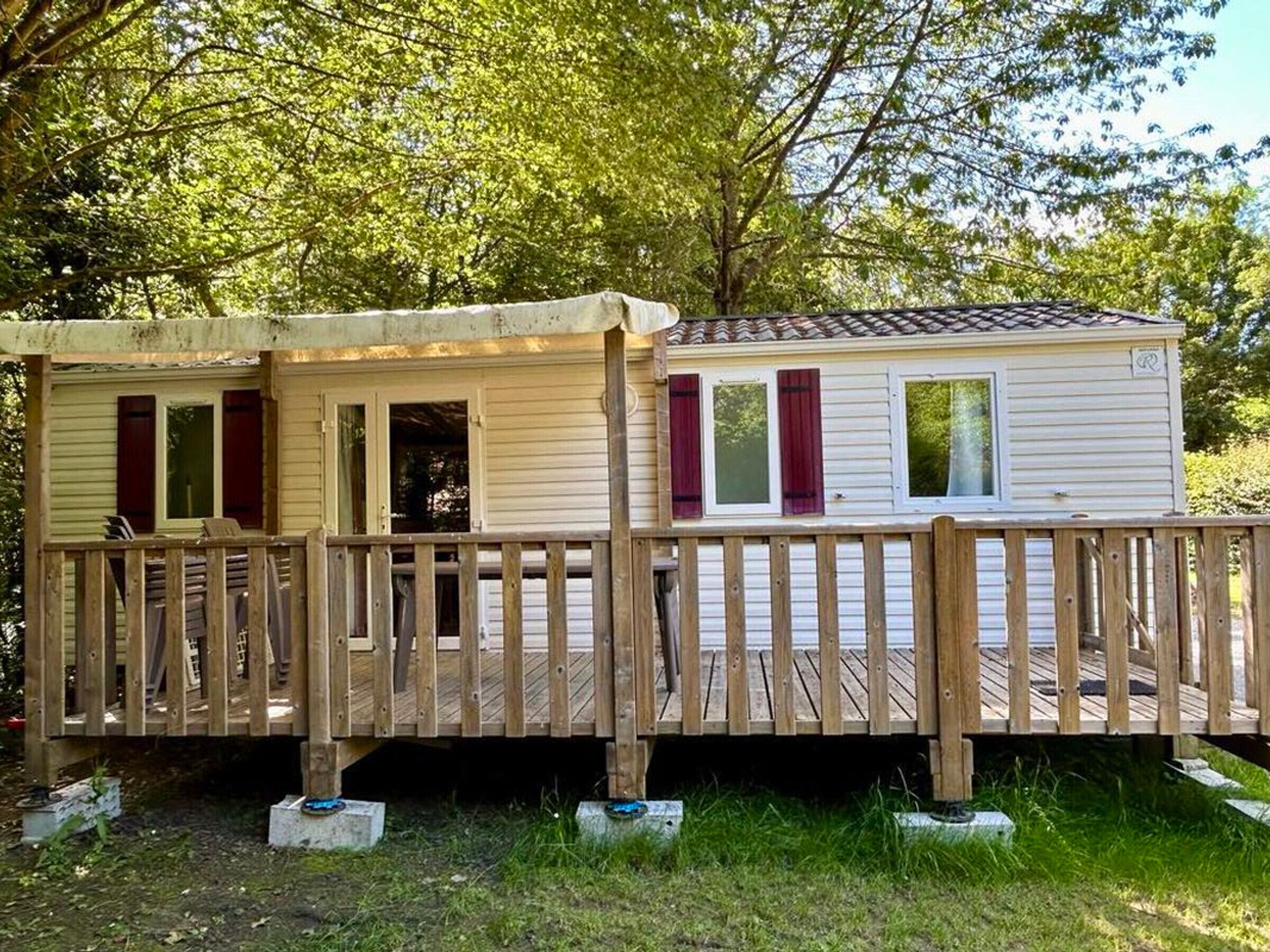 A mobile home with a wooden deck and a covered porch.