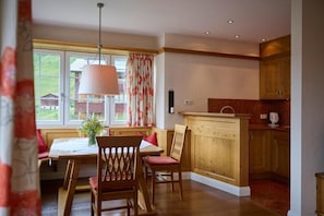 Un coin repas avec des meubles en bois, une fenêtre avec des rideaux et une cuisine avec des placards en bois.