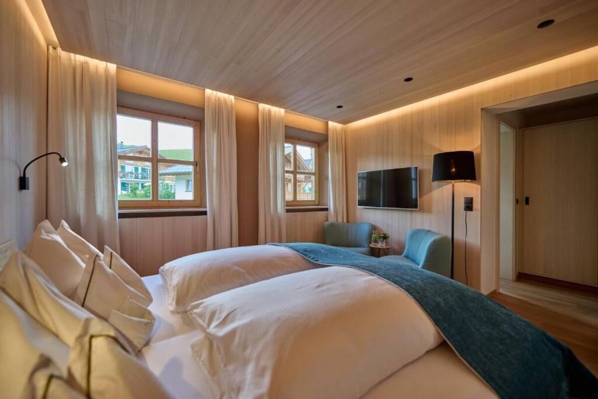 A hotel room with a large bed, a TV, a desk, and a view of the outside.