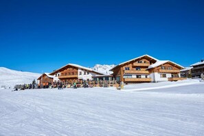 Un hôtel de style chalet, doté de nombreux balcons, avec une piste de ski en arrière-plan.