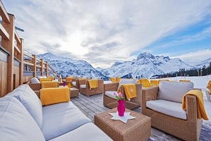 Une terrasse en bois, meublée de mobilier en osier, avec vue sur les montagnes.