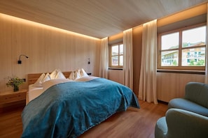 Une chambre à coucher avec un lit, une table de chevet, une fenêtre avec des rideaux et une vue sur les bâtiments à l’extérieur.