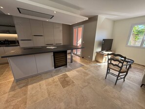 A modern kitchen with a large island, a dining area with a TV, and a view of the outdoors. - 2-bedroom house with garden and sea view in La Croix-Valmer (La Croix-Valmer)