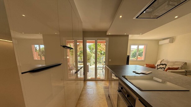 A modern kitchen with a large island, sliding doors leading to an outdoor area, and a built-in oven. - 2-bedroom house with garden and sea view in La Croix-Valmer (La Croix-Valmer)