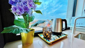 Eine Küchenarbeitsplatte mit einer Kaffeemaschine, einem Topfpflanzen und einem Tablett mit Früchten.
