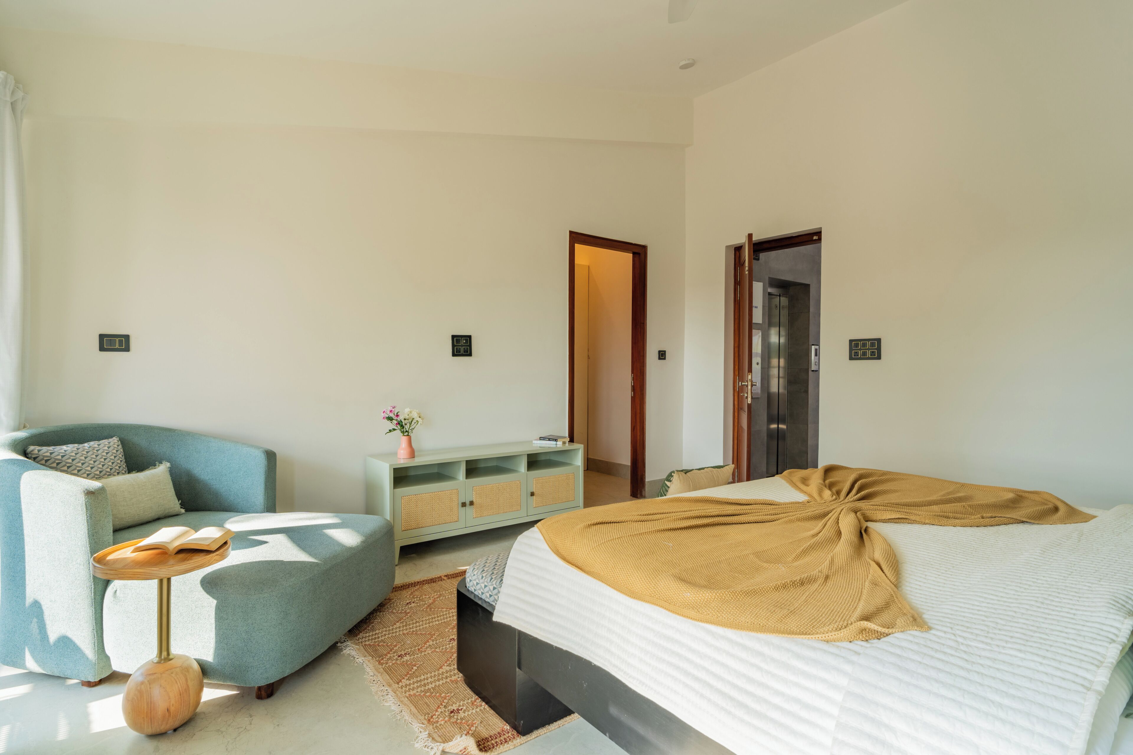 A bedroom with a bed, a sofa, a small table, and a cabinet.