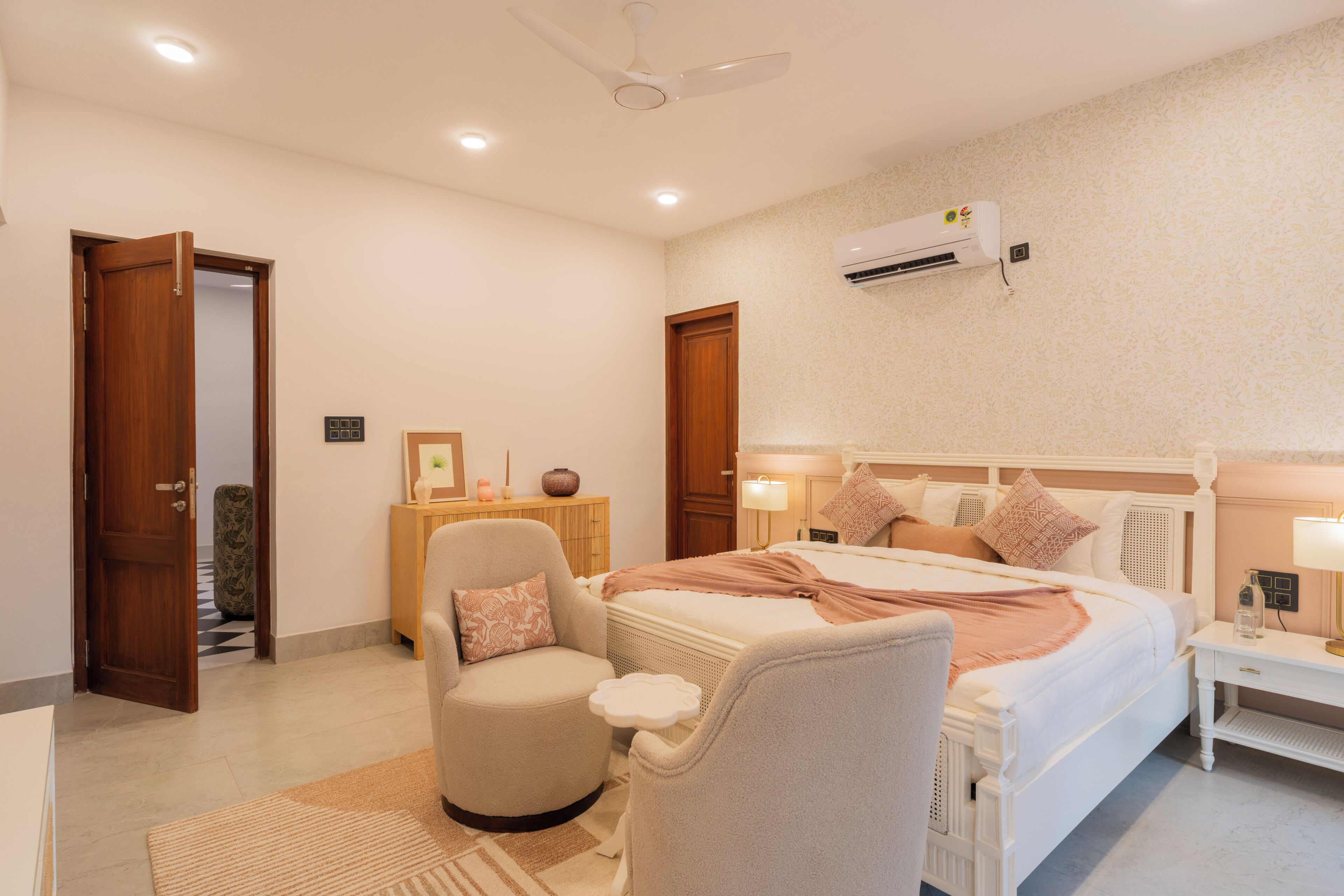 Un dormitorio con cama, mesitas de noche, una silla, ventilador de techo y aire acondicionado.