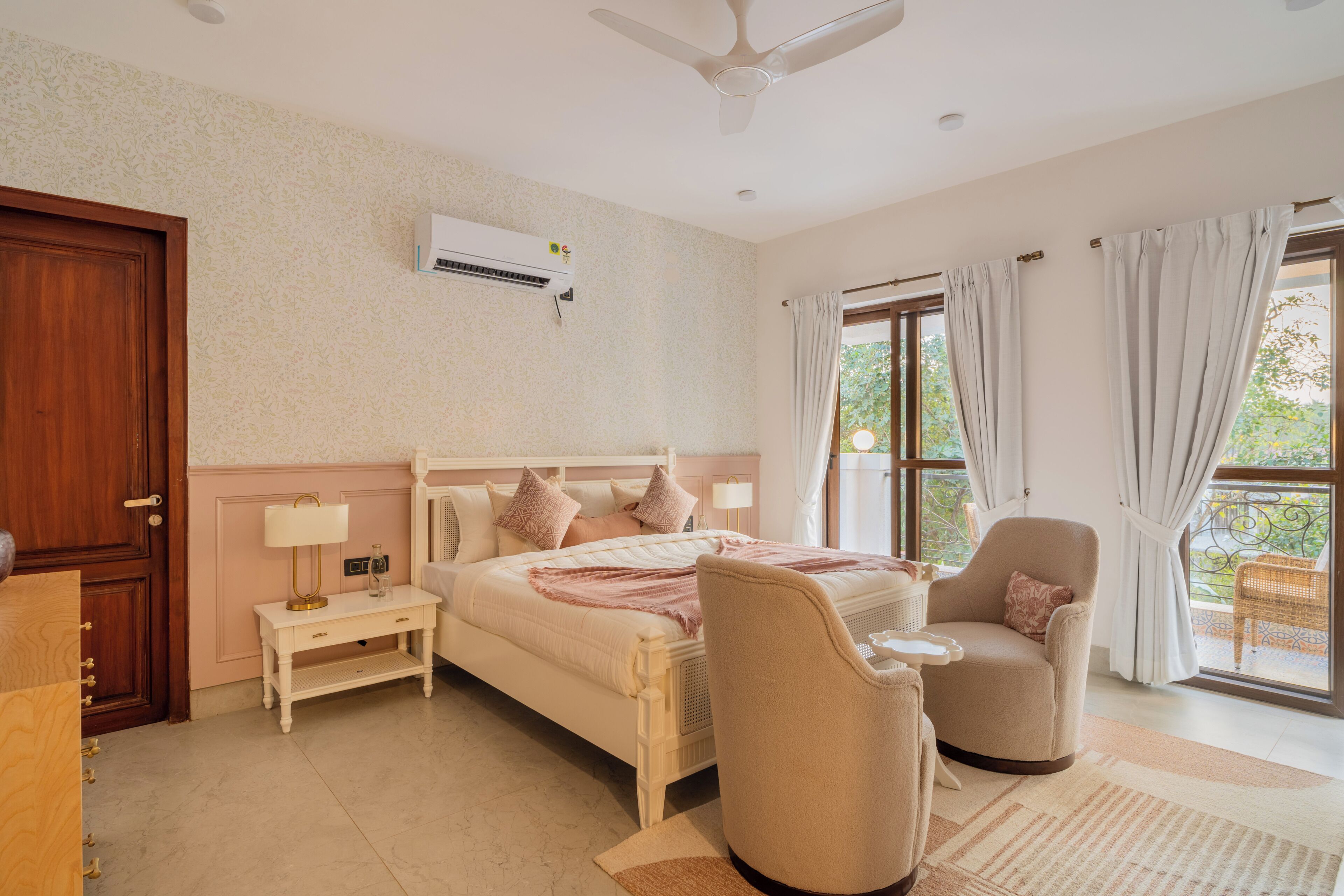Egy hálószoba, amelyben található egy ágy, éjjeliszekrények, egy szék, egy mennyezeti ventilátor és egy ablak, amelyen függöny van.