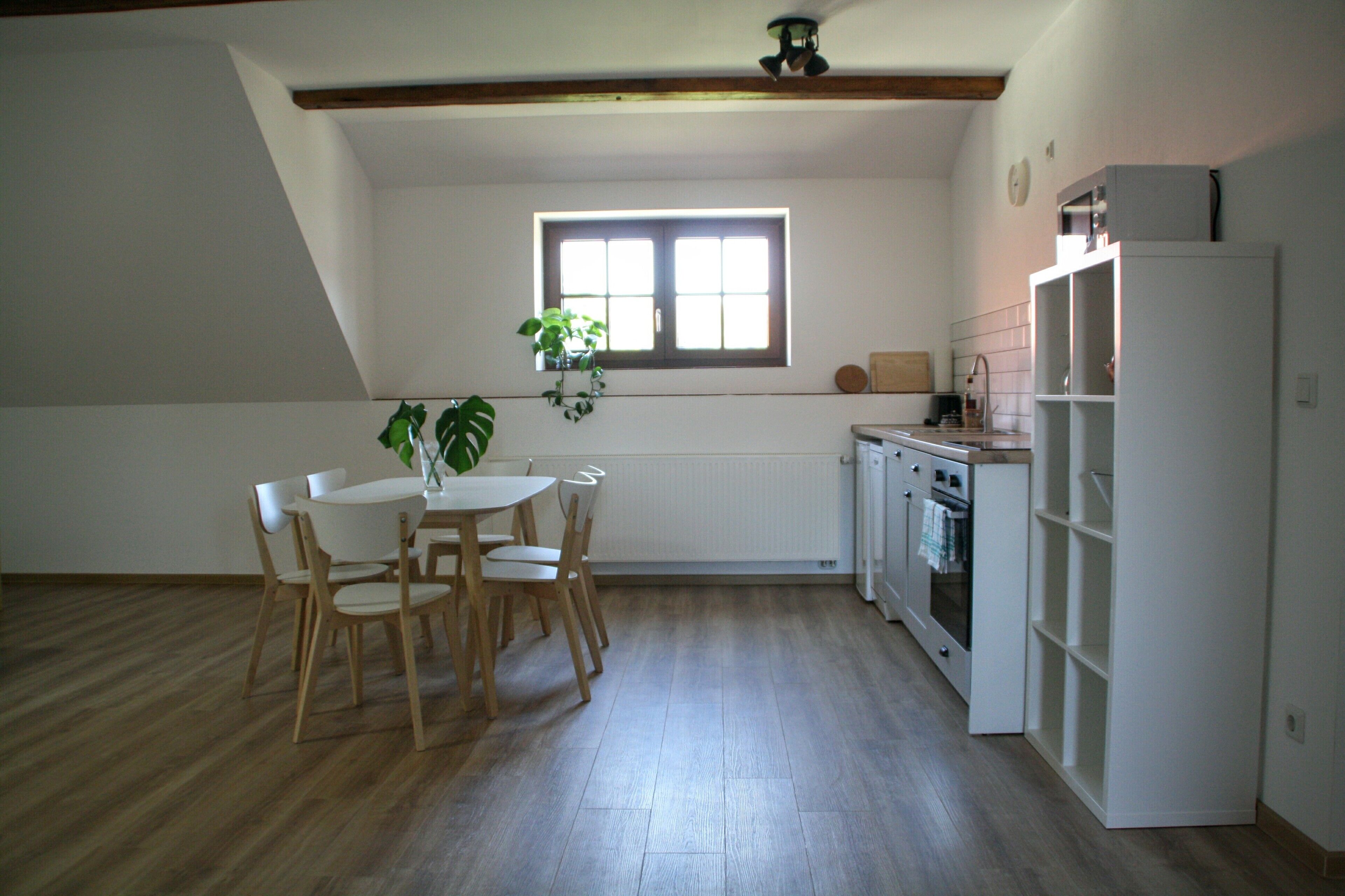 A kitchen with a dining table and chairs, a window, and a refrigerator.