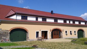A building with a red-tiled roof, multiple arched doors, and a paved courtyard. - Ferienhof Steindörfel (Hochkirch)