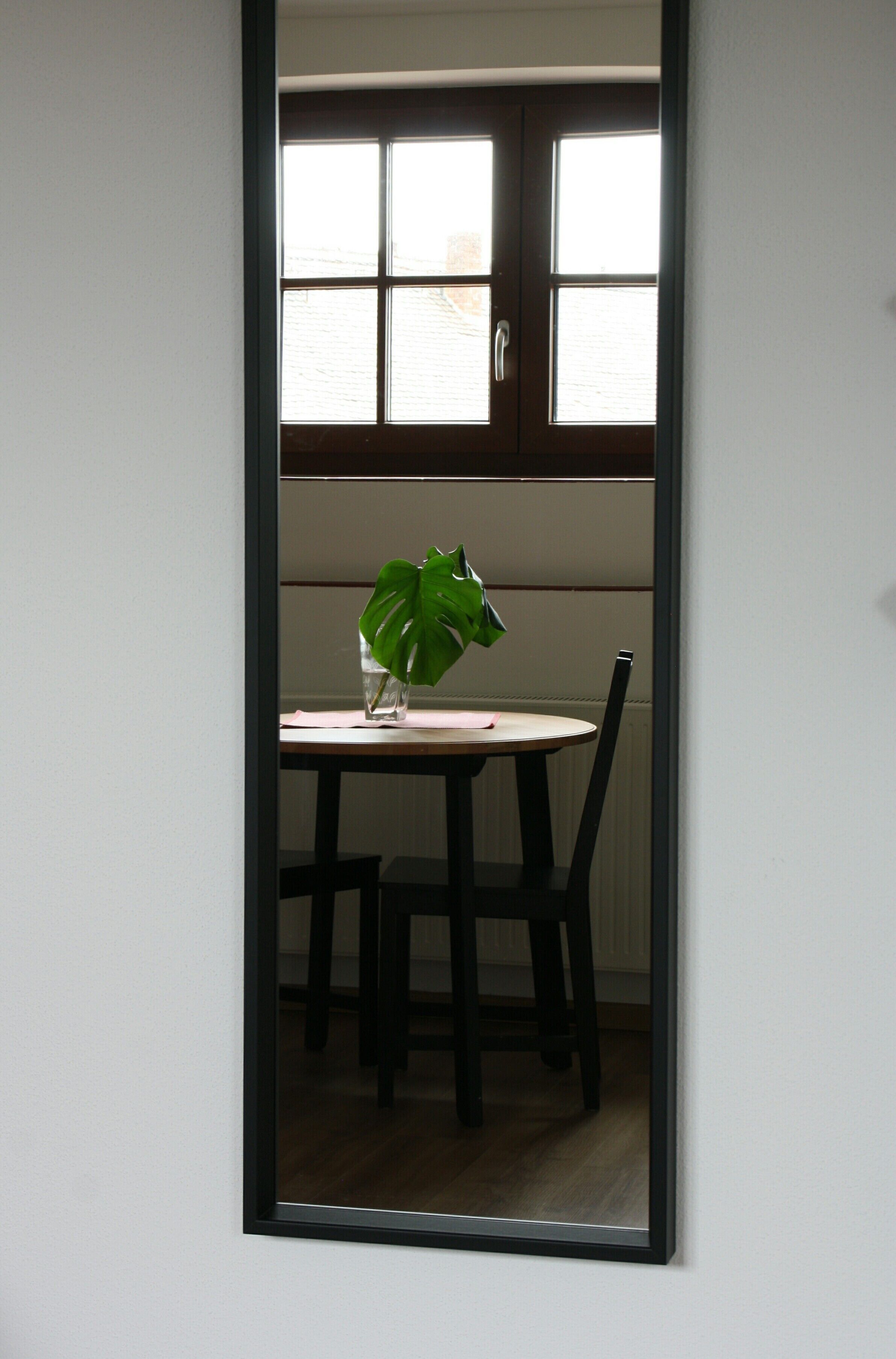 Une pièce avec une table, des chaises, une fenêtre et un miroir.