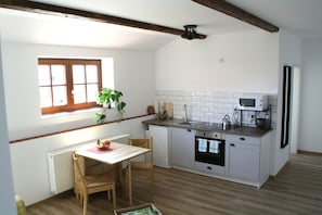 Una cocina compacta con mesa, sillas, una ventana y un microondas.