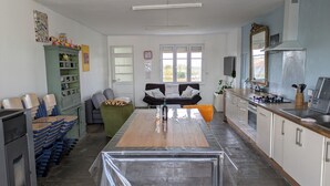 Et køkken med spisebord, stole, sofa og fjernsyn.