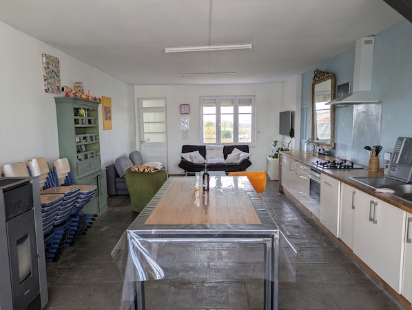 A kitchen with a dining table, chairs, a sofa, and a TV.