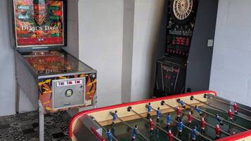 Une pièce équipée d’un baby-foot, d’un jeu de fléchettes et d’un flipper.