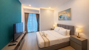 Una habitación de hotel con cama, lámparas de noche, televisor sobre un mueble y un cuadro en la pared.