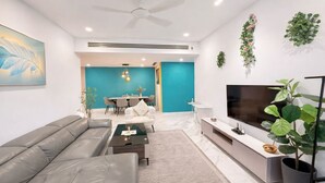 Una sala de estar moderna con un sofá, una mesa de centro, un televisor y un comedor con sillas y una mesa.