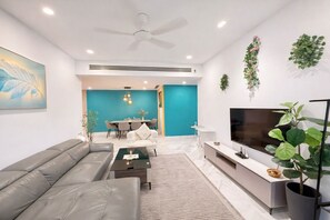 Ein modernes Wohnzimmer mit Sofa, Couchtisch, Fernseher und einem Essbereich mit Stühlen und Tisch.