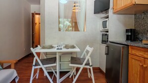 A compact kitchen with a dining table, chairs, a refrigerator, and a television mounted on the wall. - Your comfortable shelter with pool - Herbasabina 2 (Pla de l'Ermita)