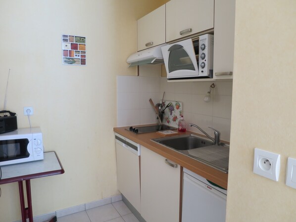 A compact kitchen with a microwave, oven, sink, and a Bosch dishwasher.