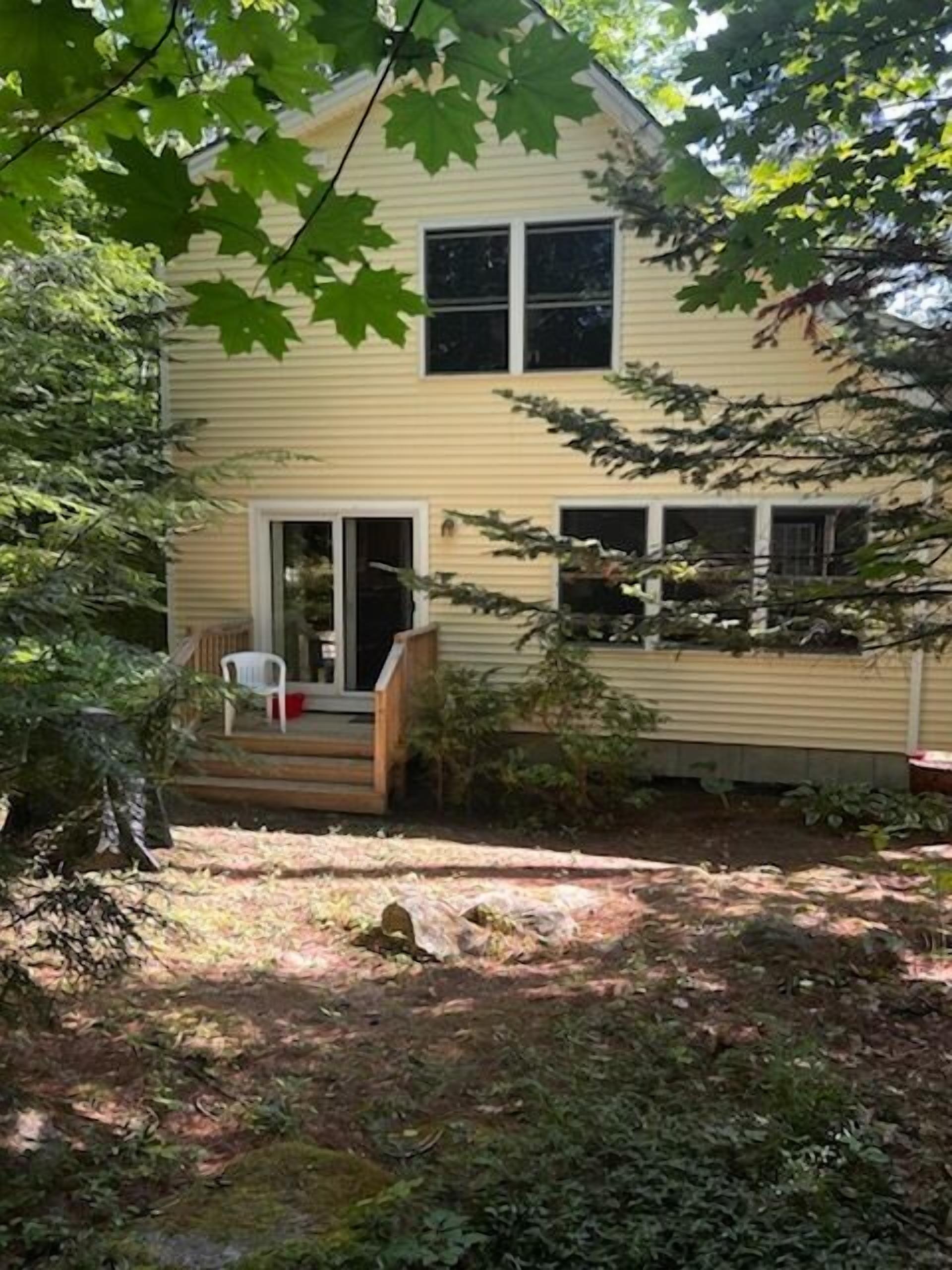 A two-story house with a front porch, a sliding glass door, and a small garden area.