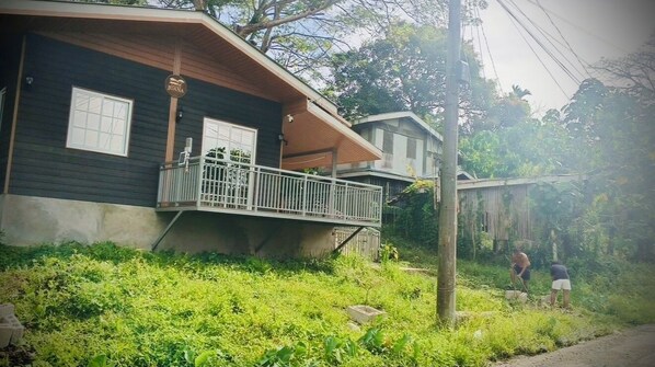 A two-story house with a balcony, surrounded by greenery.