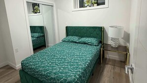 Un dormitorio con cama, ventana con vistas, espejo y mesita de noche.