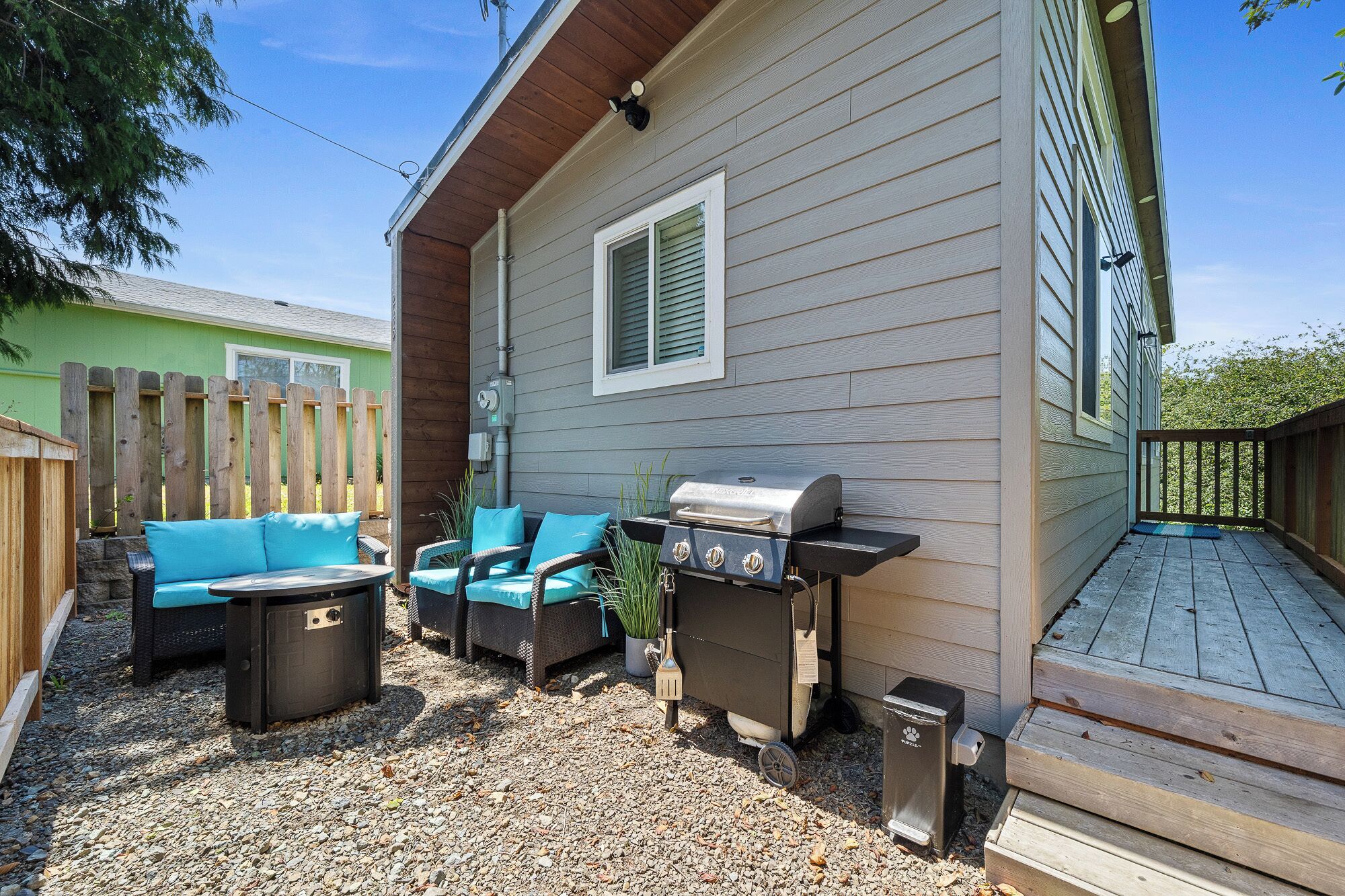 A patio with a grill, outdoor furniture, and a wooden deck.