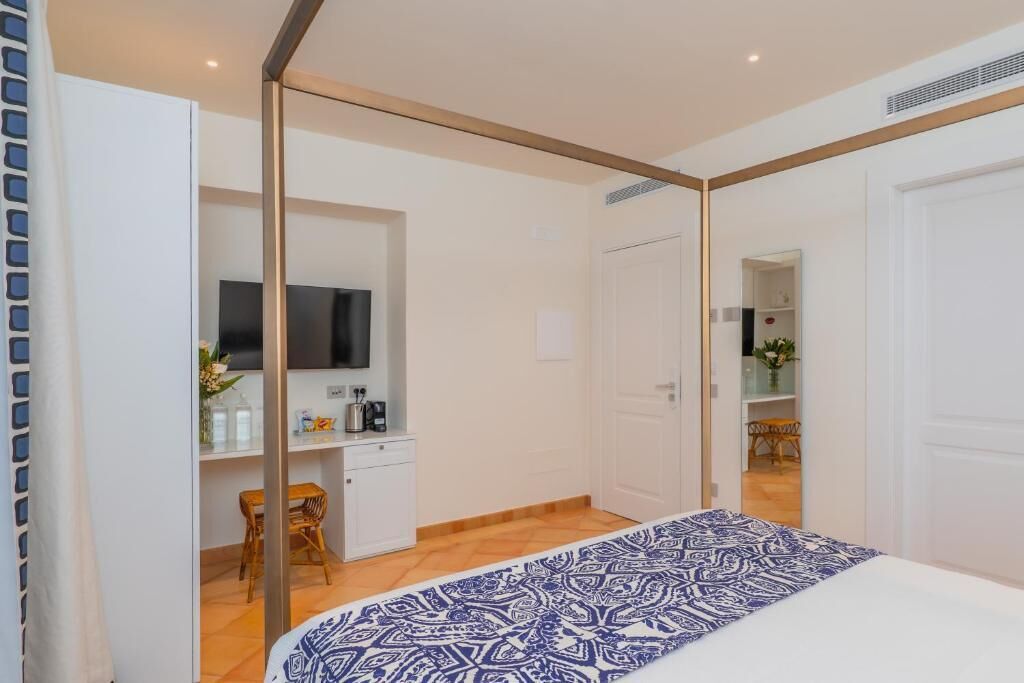 Una camera da letto con un letto, una scrivania con una sedia, una televisione e una porta che dà su un bagno.