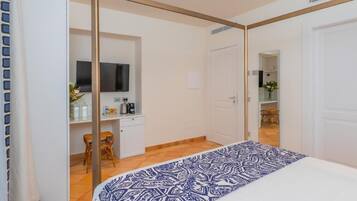 Una camera da letto con un letto, una scrivania con una sedia, una televisione e una porta che dà su un bagno.