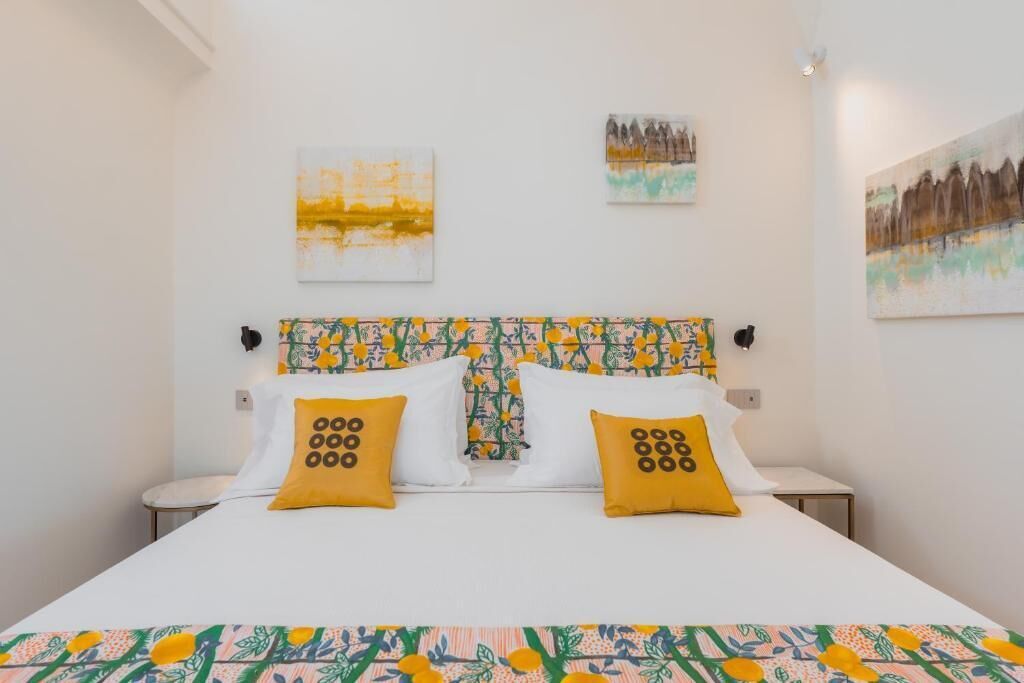 A bed with a patterned headboard, two pillows with circular designs, and a floral bedspread.