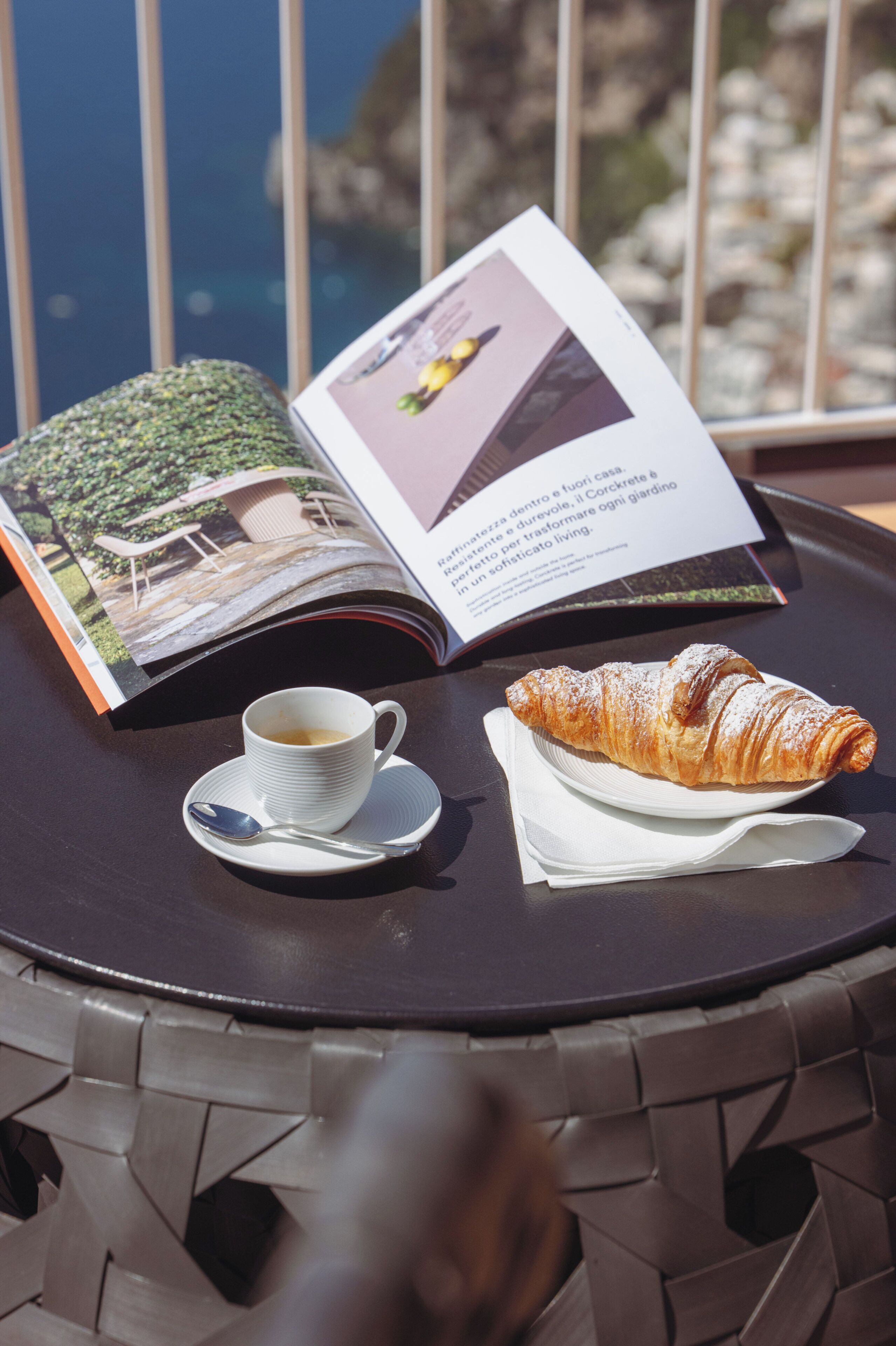 Ett bord med ett croissant, en kopp kaffe och en öppen tidning.