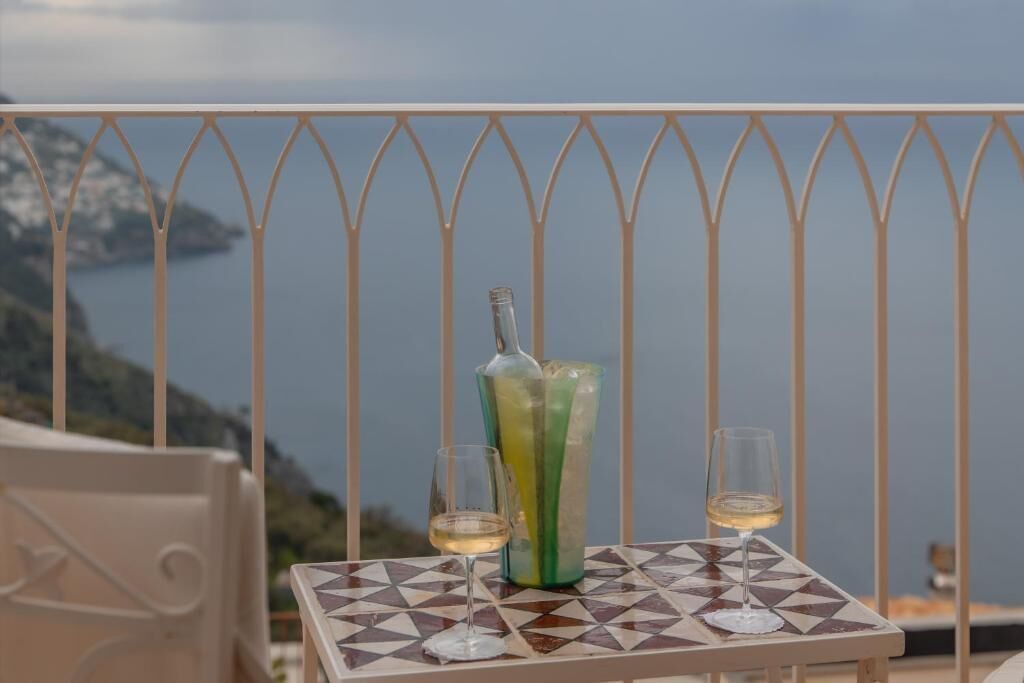 A balcony with a table, two glasses, and a bottle.