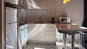 Une cuisine compacte au design moderne, dotée d’un four encastré, d’un four à micro-ondes et d’un évier.