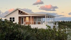 Una casa costanera amb un porxo cobert, grans finestres i vistes al mar.
