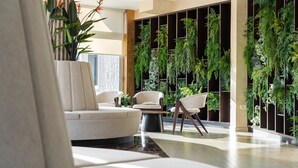 En moderne lobby med siddeområde, lodret have og et stort vindue.