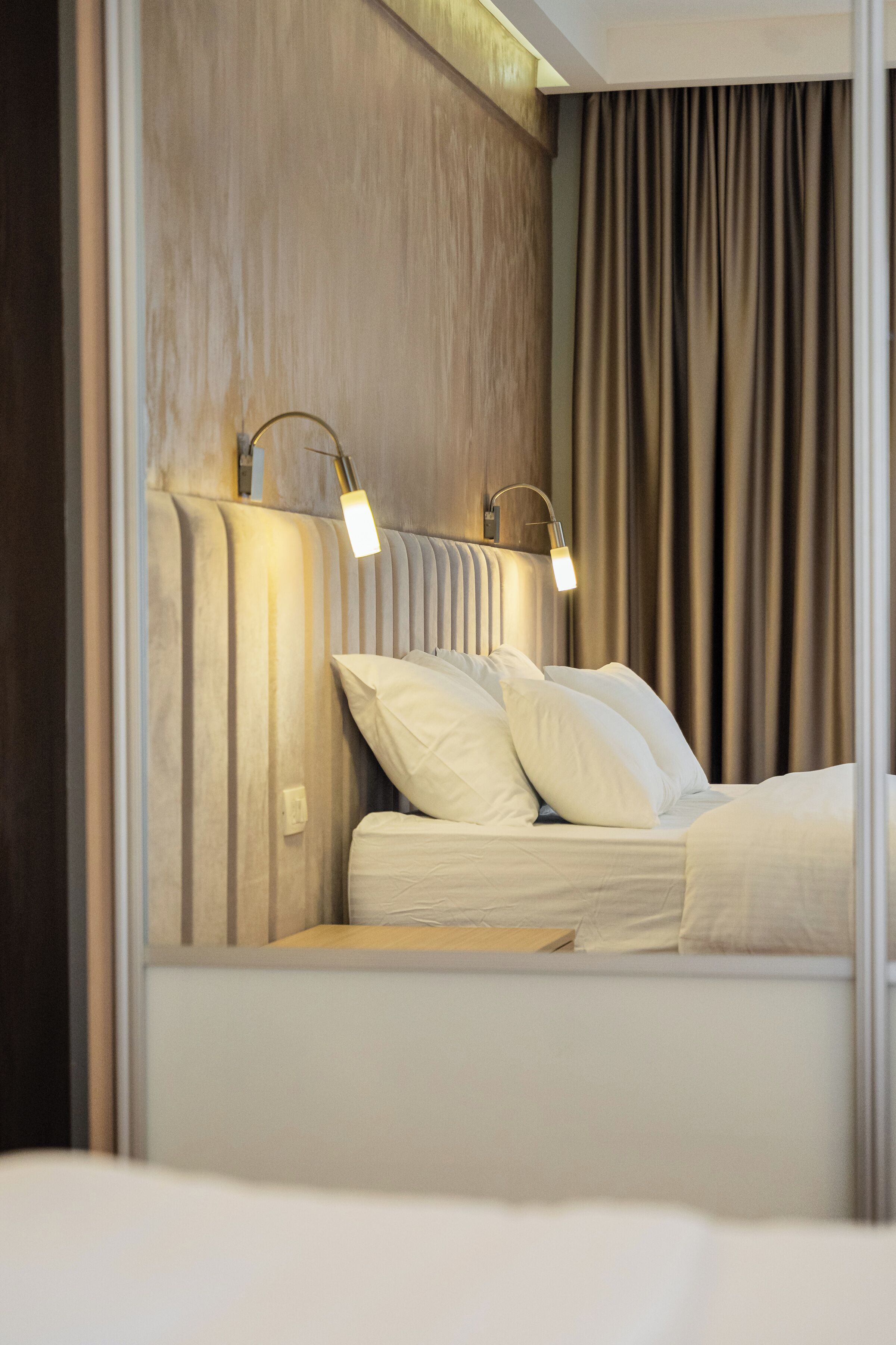 Une chambre d’hôtel moderne avec un lit, une tête de lit et deux lampes de chevet.