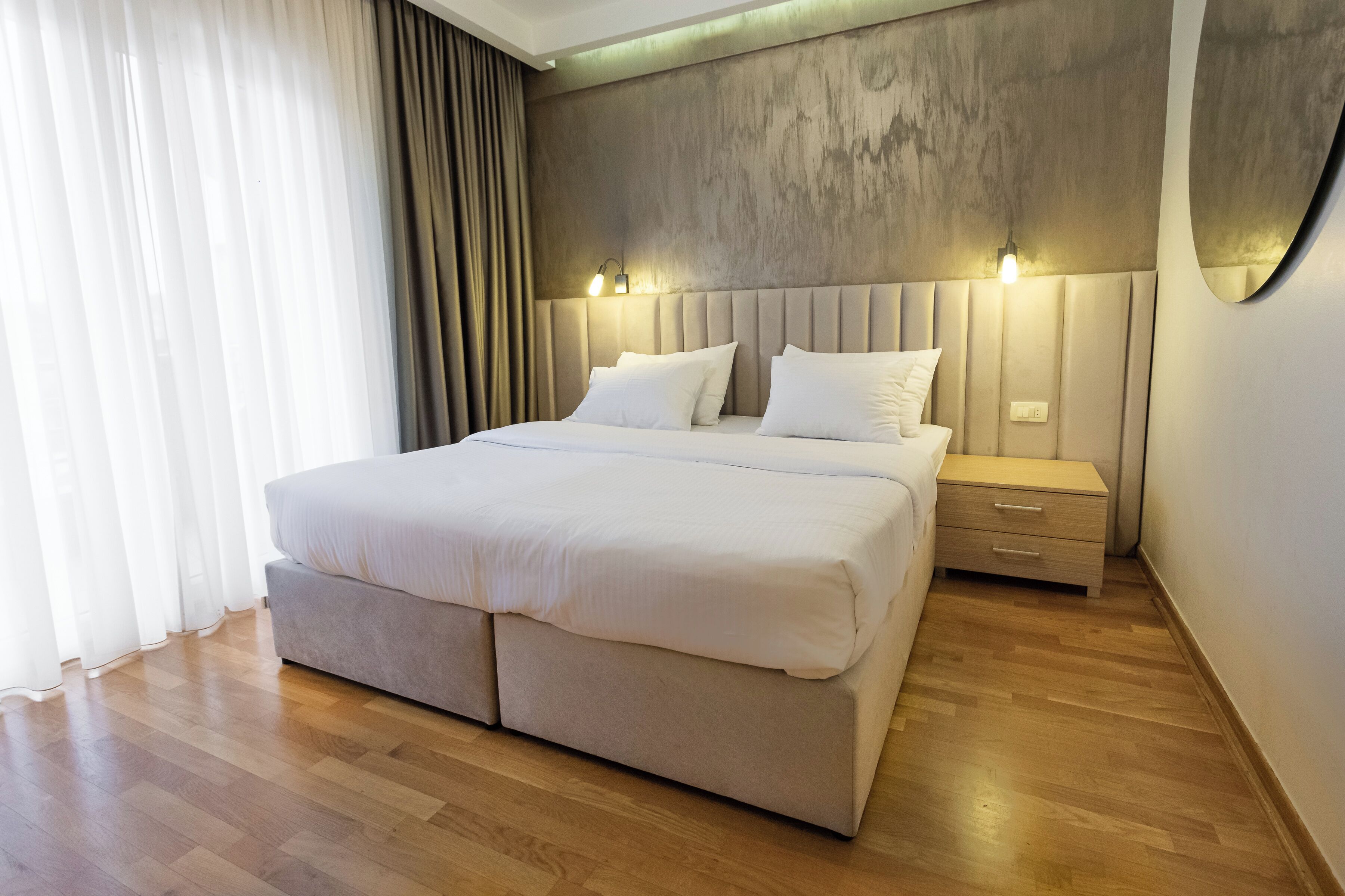 A modern bedroom with a large bed, bedside tables, and a wooden floor.