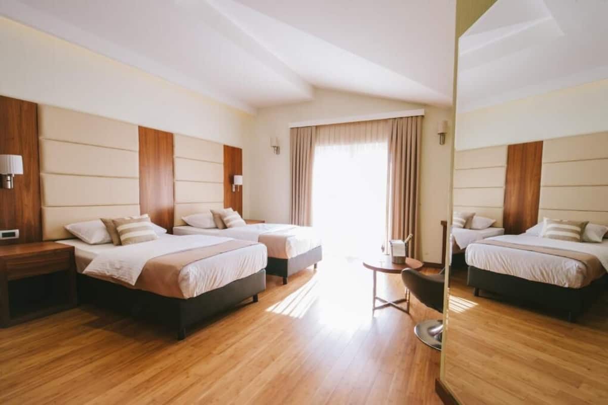 A hotel room with two beds, a small table, and a chair.