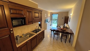 A kitchen with wooden cabinets, a microwave, a stove, and a dining area with a table and chairs.